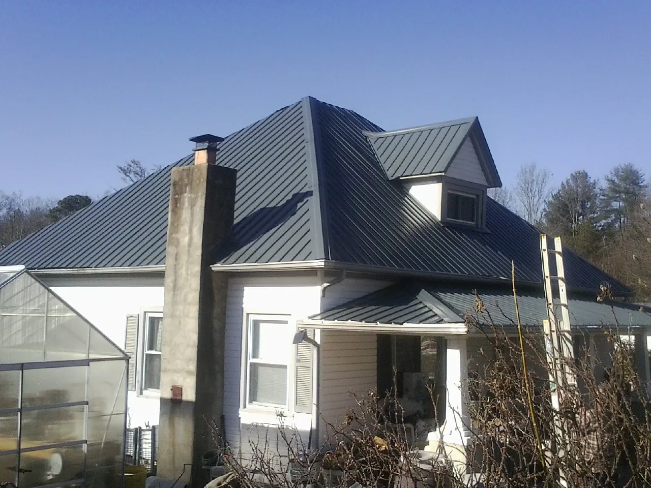 Dark blue standing seam metal roof on a white farmhouse with dormer — Slate & Tile Roof Repair by Roofing Brothers in Lynchburg