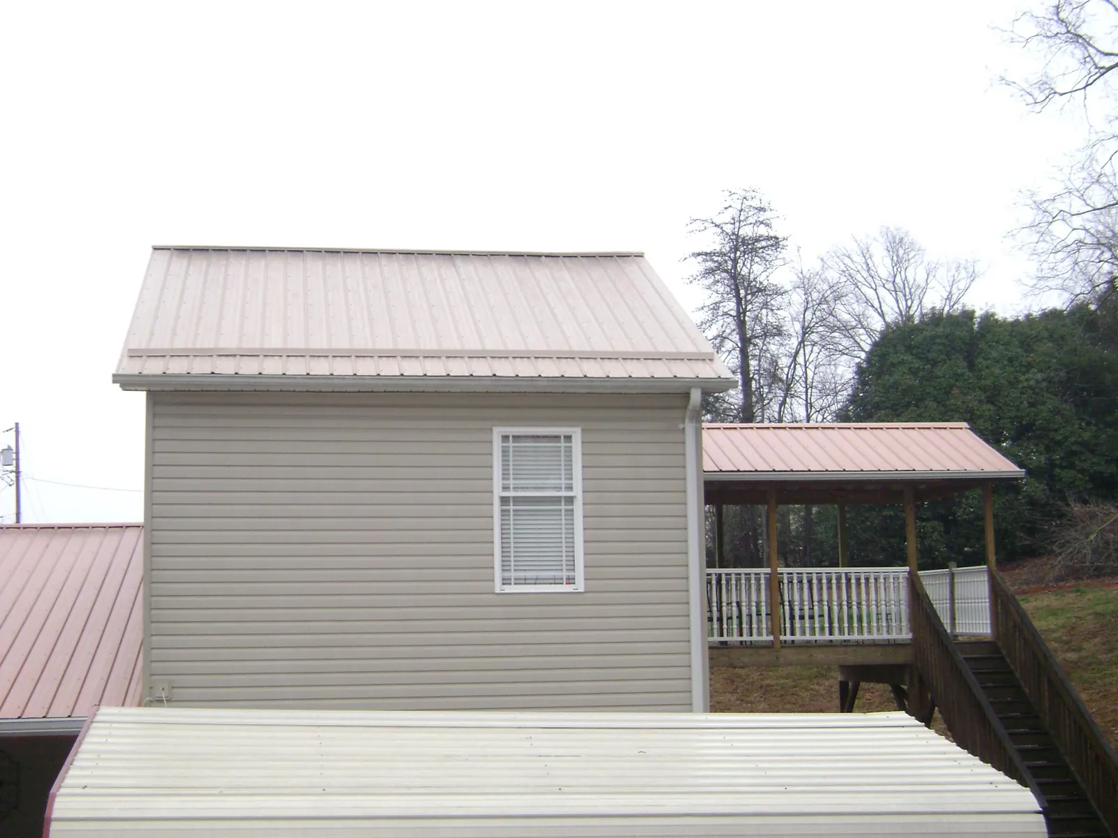 Tan metal roofs on a two story addition and attached porch, from a Roof Replacement job in Lynchburg